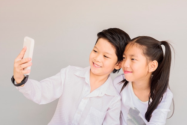 Los niños asiáticos preciosos de la escuela de la pareja están tomando el selfie