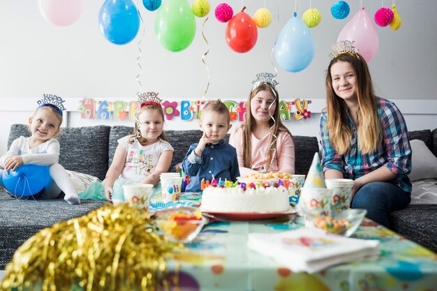 Niños bonitos sonriendo junto a la mesa dulce de cumpleaños