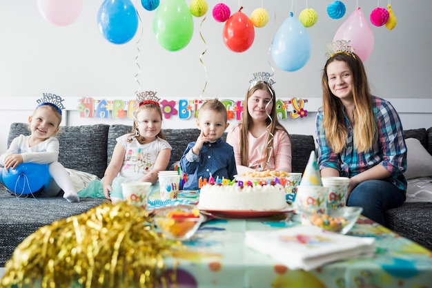 Niños bonitos sonriendo junto a la mesa dulce de cumpleaños