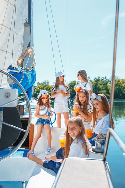 Los niños a bordo del yate de mar bebiendo jugo de naranja.