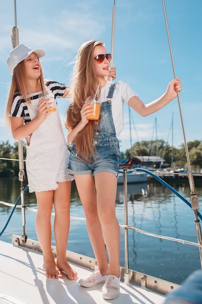 Los niños a bordo del yate de mar bebiendo jugo de naranja.