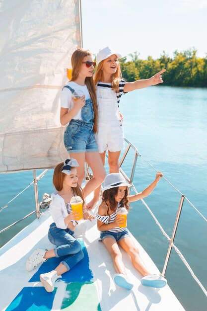 Niños a bordo del yate de mar bebiendo jugo de naranja