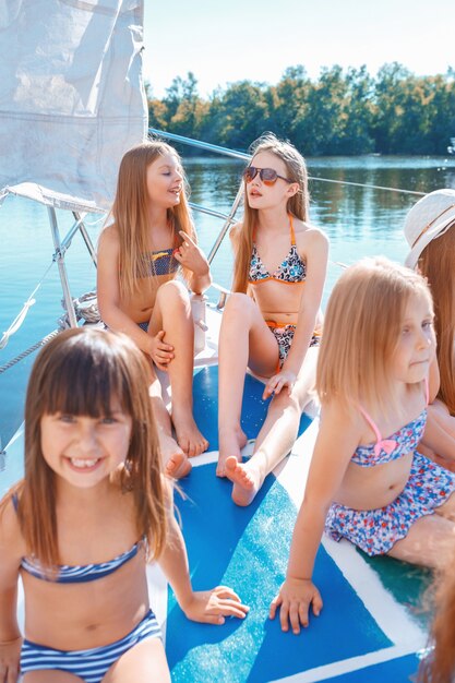 Los niños a bordo del yate de mar. Las niñas adolescentes o niños contra el cielo azul al aire libre. Ropa de colores. Moda infantil, verano soleado, conceptos de río y vacaciones.