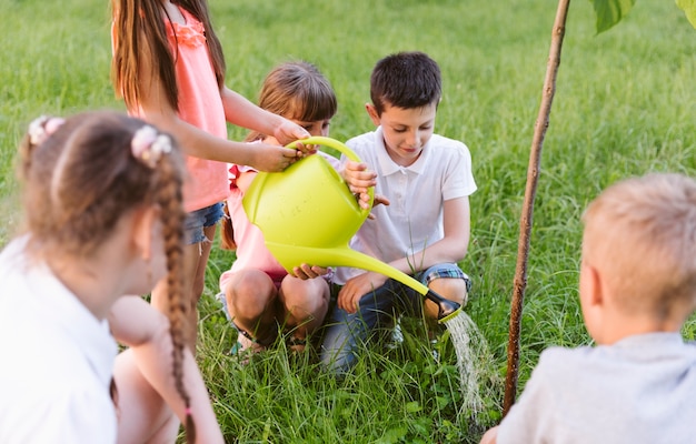 Niños chapando y regando árboles