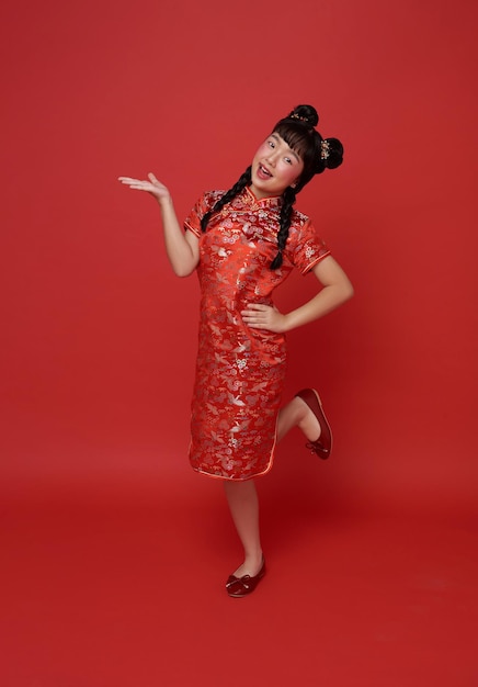 Foto gratuita niños chica asiática en rojo tradicional cheongsam qipao con el gesto de bienvenida al año nuevo chino 2024