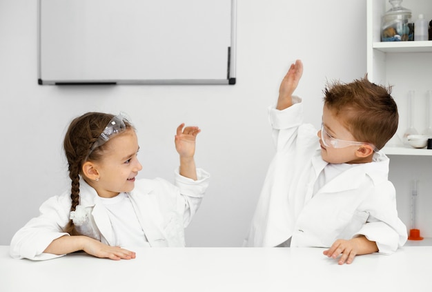 Foto gratuita niños científicos que se divierten haciendo experimentos y chocando los cinco