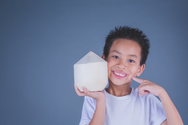 Foto gratuita los niños comen agua de coco sobre un fondo gris.