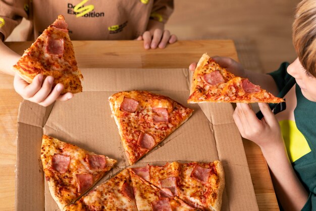 Niños comiendo pizzas juntos