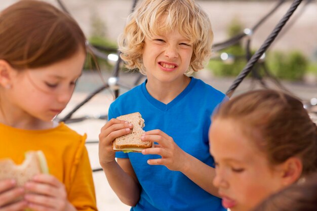 Niños comiendo sándwiches juntos de cerca