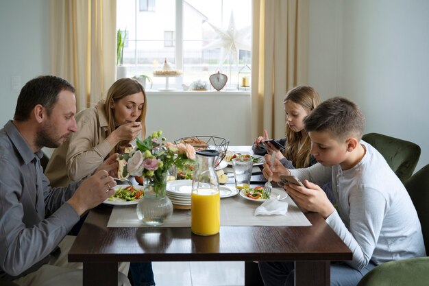 Niños comiendo con vista lateral del teléfono inteligente