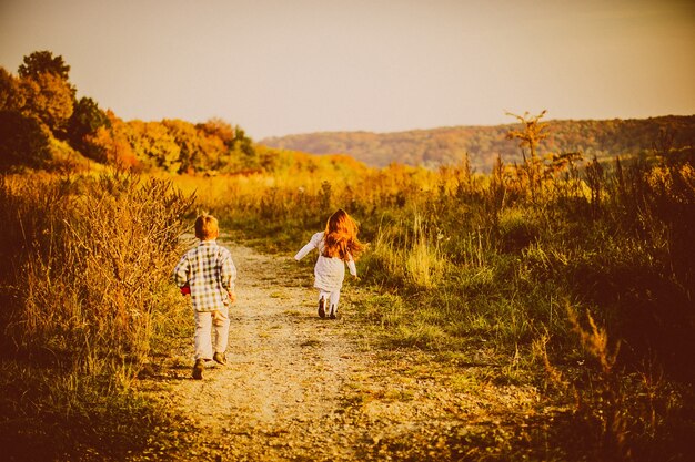 Los niños corren a través de un campo de otoño