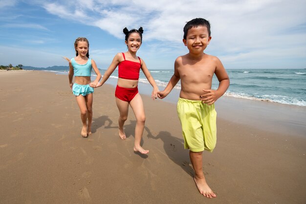 Niños corriendo en la playa tiro completo