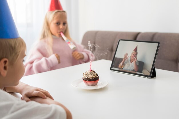 Niños en cuarentena en casa celebrando cumpleaños sobre tableta