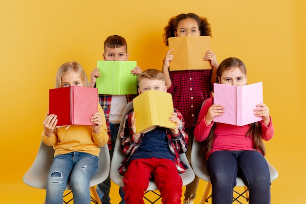 Niños cubriendo caras con libros