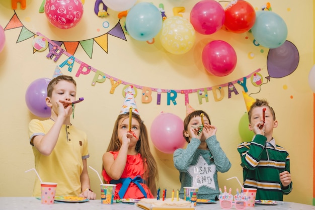 Niños con cuernos de fiesta celebrando cumpleaños