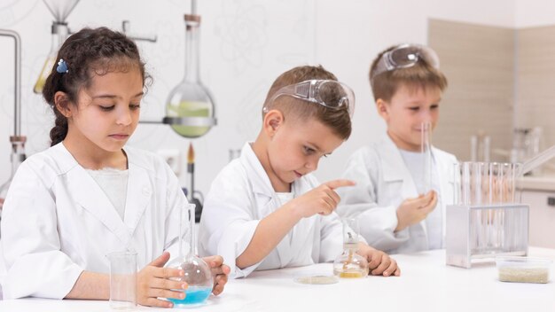 Niños curiosos haciendo un experimento químico en la escuela.