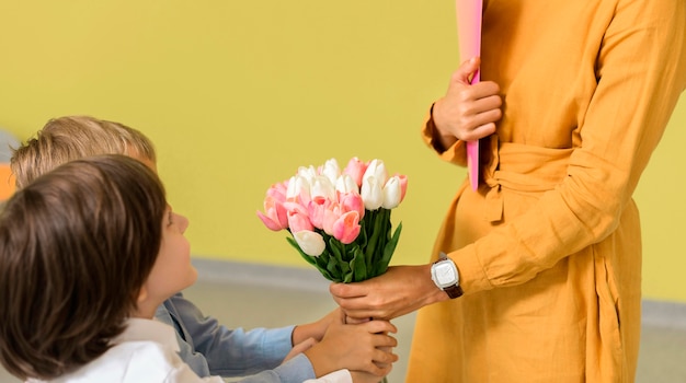 Niños dando a su maestra un ramo de flores.