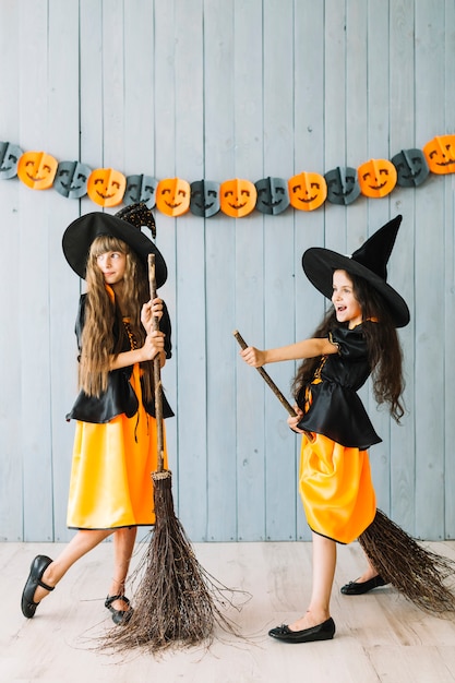 Foto gratuita niños disfrazados de brujas sosteniendo palos de escoba