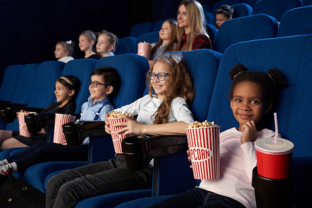 Niños disfrutando de estreno en el cine.