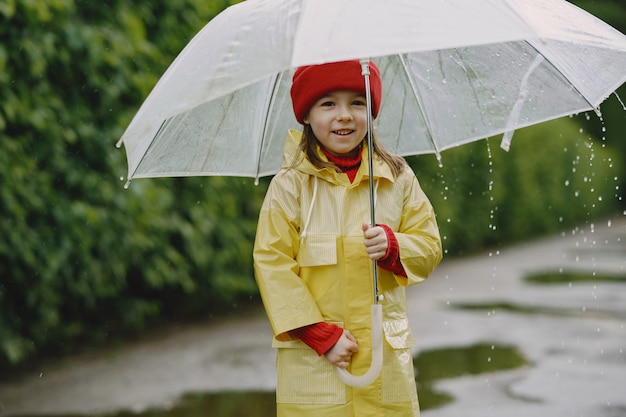 Niños divertidos en botas de lluvia jugando junto a un charco