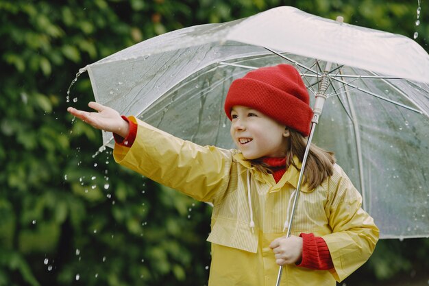 Niños divertidos en botas de lluvia jugando junto a un charco