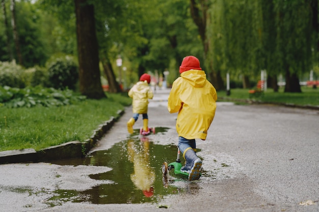 Niños divertidos con botas de lluvia jugando con patines