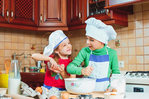 Foto gratuita niños divertidos de la familia feliz están preparando la masa, hornear galletas en la cocina