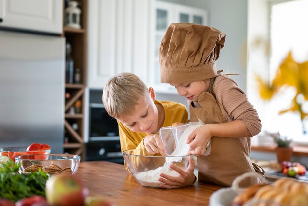 Niños divirtiéndose cocinando en la cocina de casa