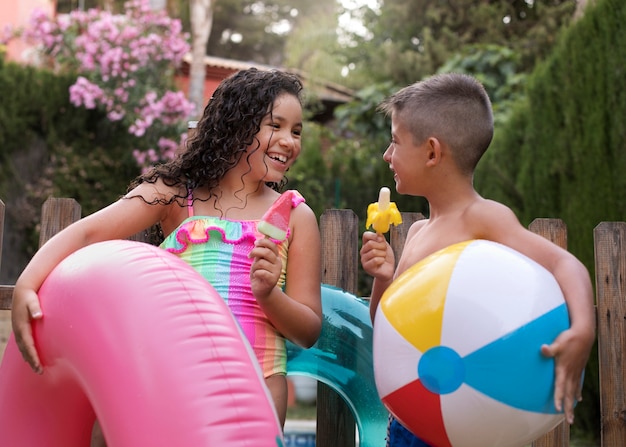Foto gratuita niños divirtiéndose con un flotador junto a la piscina