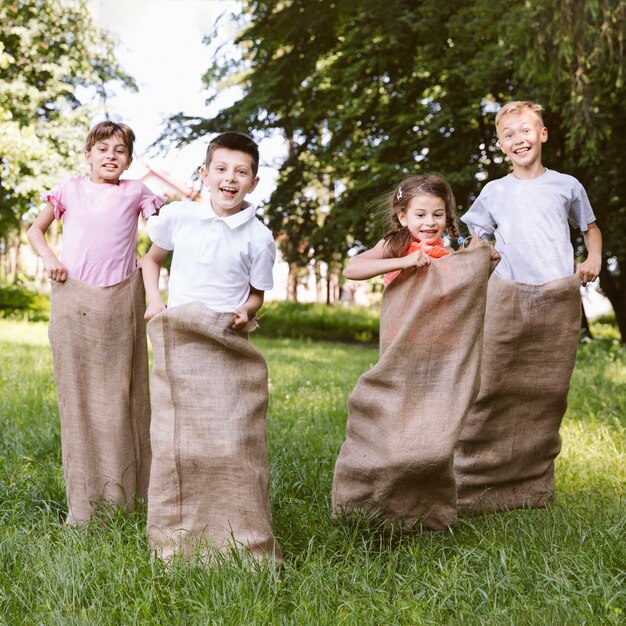 Niños divirtiéndose jugando con bolsas de arpillera