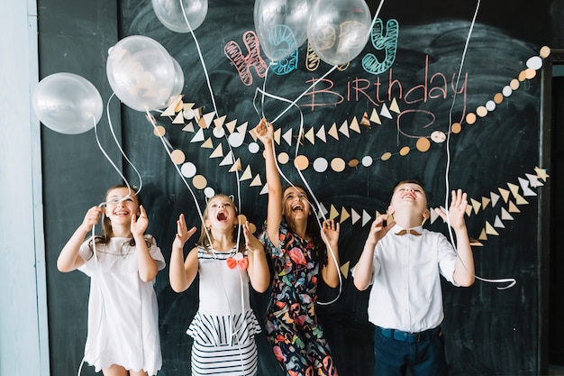 Niños emocionados soltando globos en la fiesta