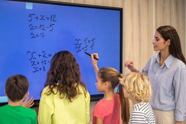 Niños escribiendo en pizarra y atento maestro mirando