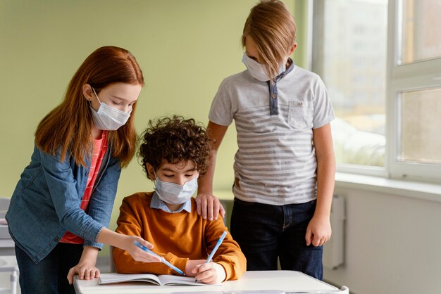 Niños en la escuela aprendiendo con máscaras médicas