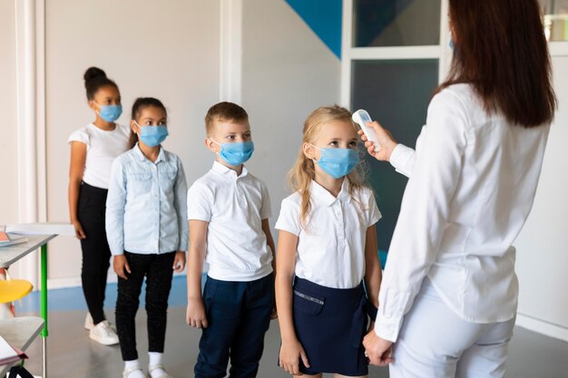 Niños esperando en fila para mediciones de temperatura