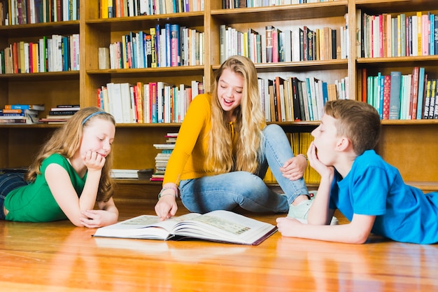 Niños estudiando un libro interesante en la biblioteca