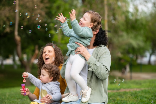 Niños felices al aire libre en el parque con madres lgbt