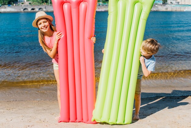 Niños felices con colchones inflables en la playa.