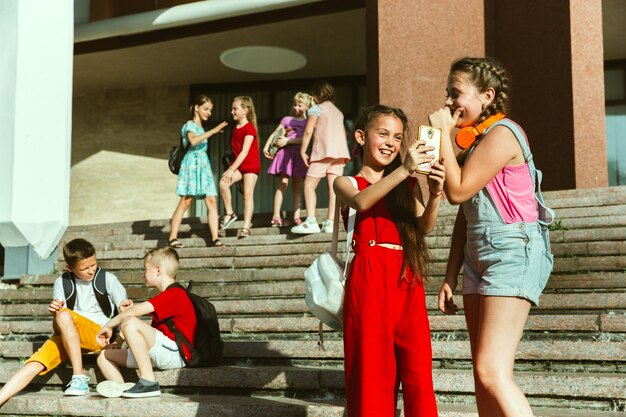 Niños felices jugando en la calle de la ciudad en un día soleado de verano frente al edificio moderno