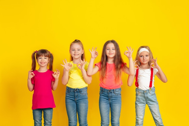 Niños felices jugando y divirtiéndose juntos en la pared amarilla