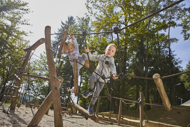 Niños felices jugando en el patio de recreo bajo la supervisión de los padres.