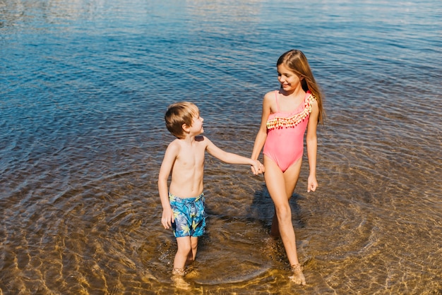 Niños felices de pie en el agua en la playa