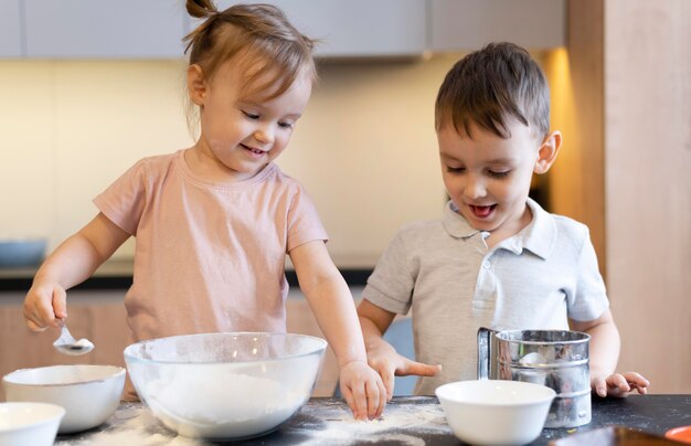 Niños felices de tiro medio en la cocina