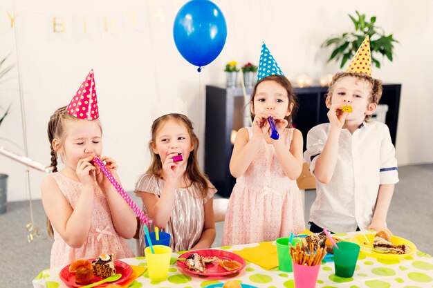 Niños en fiesta soplando juguetes