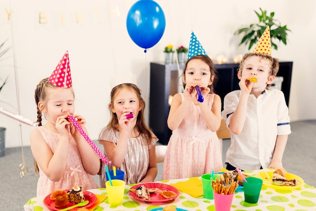 Niños en fiesta soplando juguetes