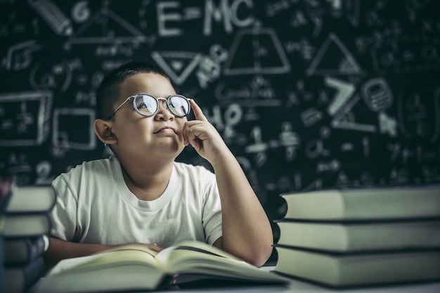 Los niños con gafas escriben libros y piensan en el aula.