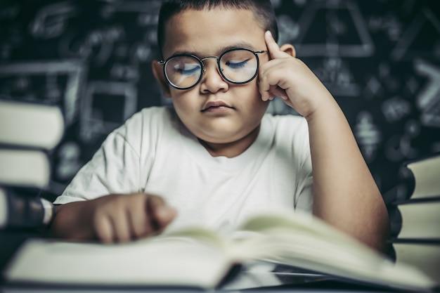 Foto gratuita los niños con gafas escriben libros y piensan en el aula.