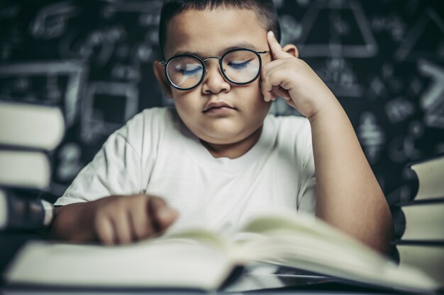 Los niños con gafas escriben libros y piensan en el aula.