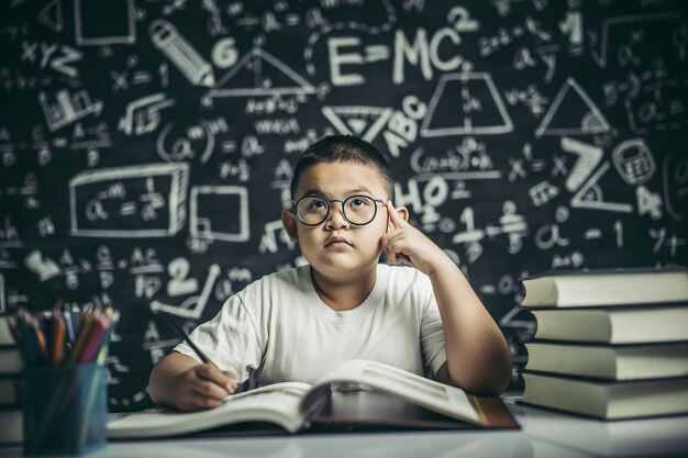 Los niños con gafas escriben libros y piensan en el aula.