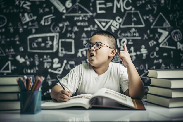 Los niños con gafas escriben libros y piensan en el aula.