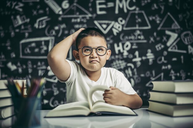 Los niños con gafas escriben libros y piensan en el aula.